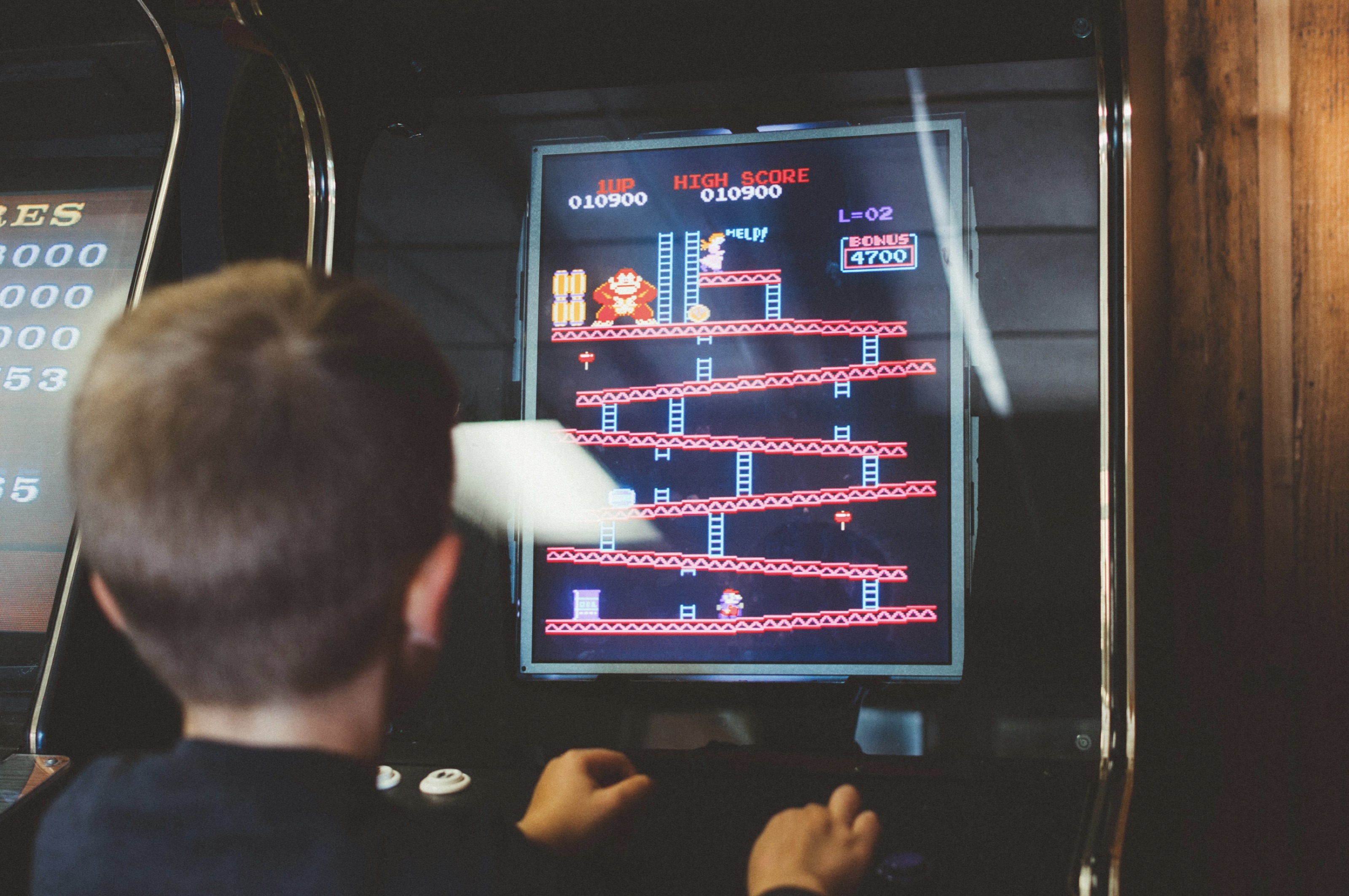 child in front of an 80's arcade cabinet - Donkey Kong