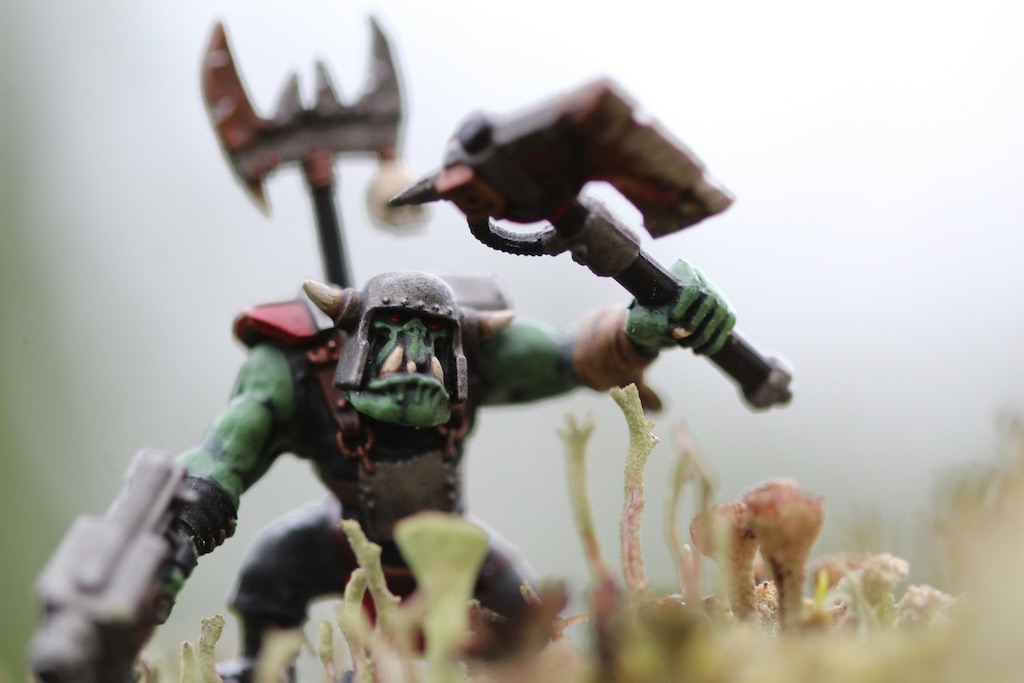 A monster (ork) brandishing a battle-axe and laser pistol